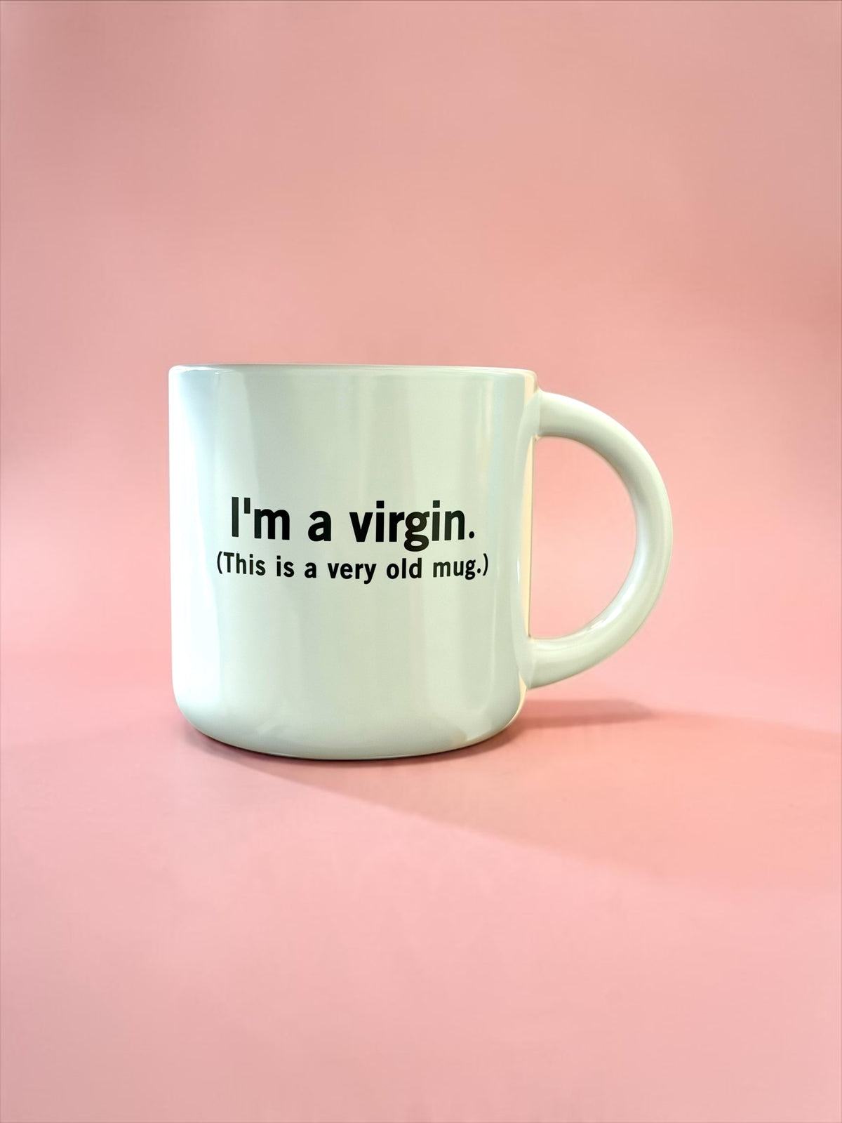 A light mint green ceramic mug with black printed text reading 'I'm a virgin. (This is a very old mug.